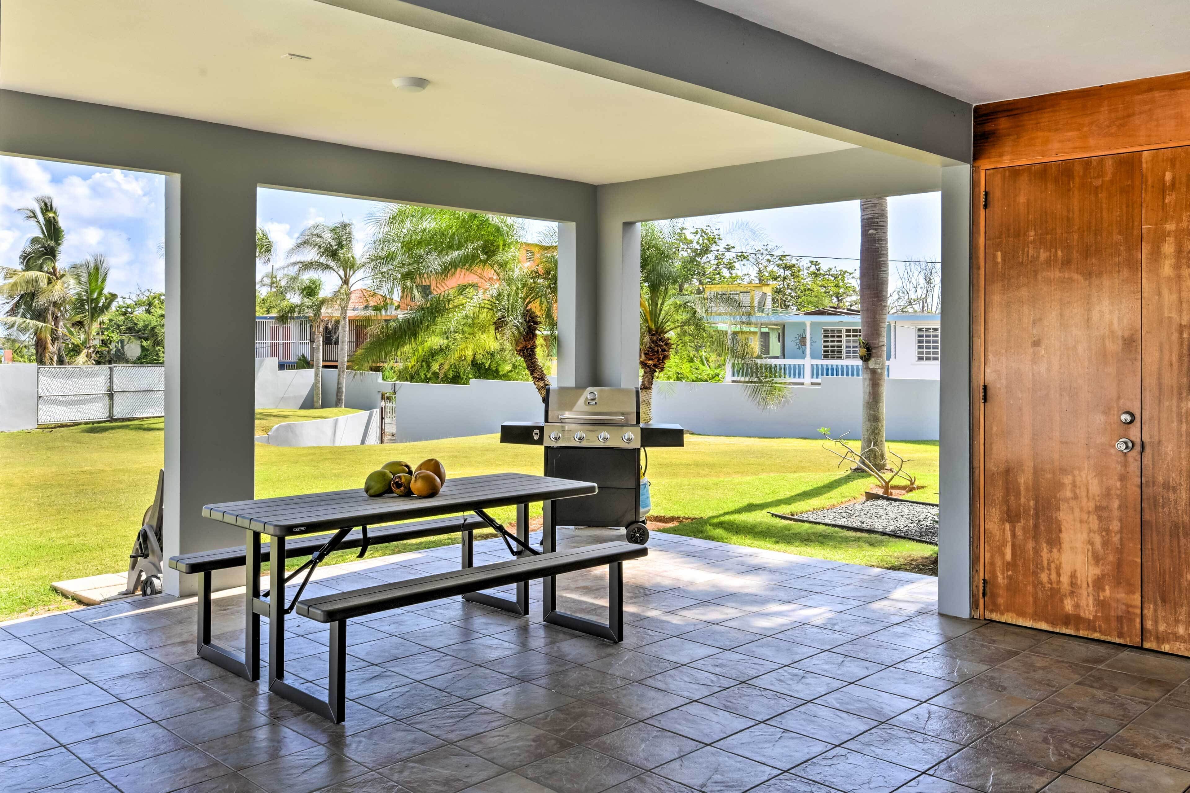 An outdoor patio with a grill, a table, and benches.