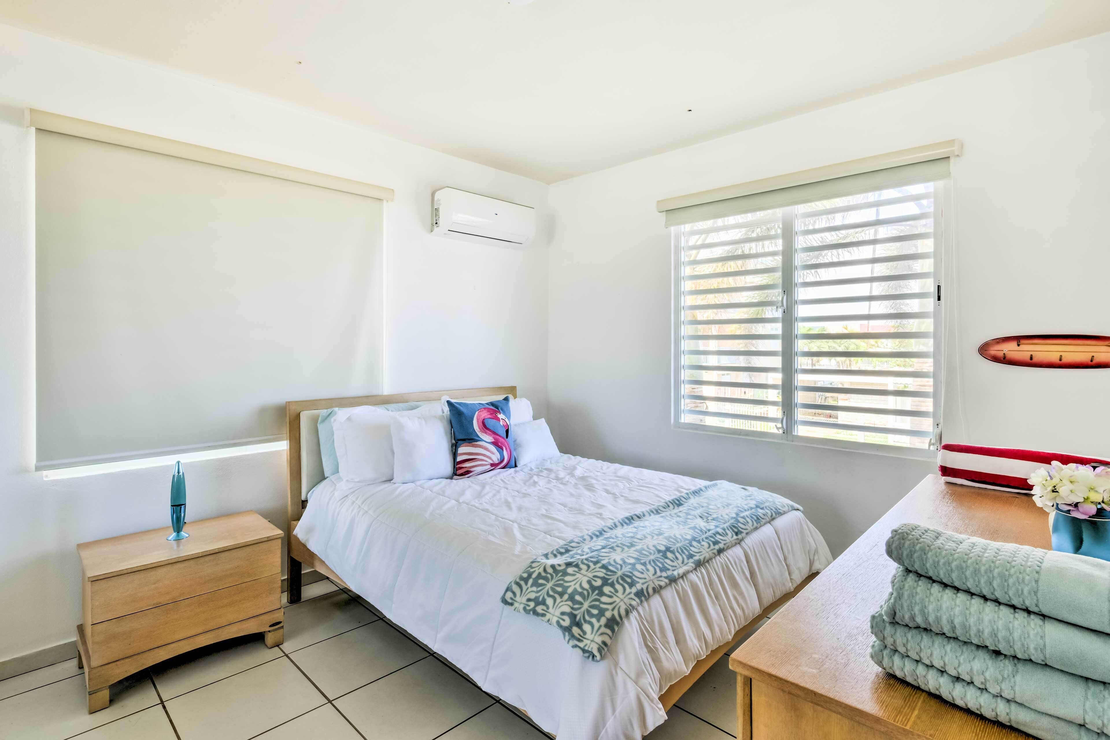 A bedroom with a bed, bedside table, and a window with blinds.