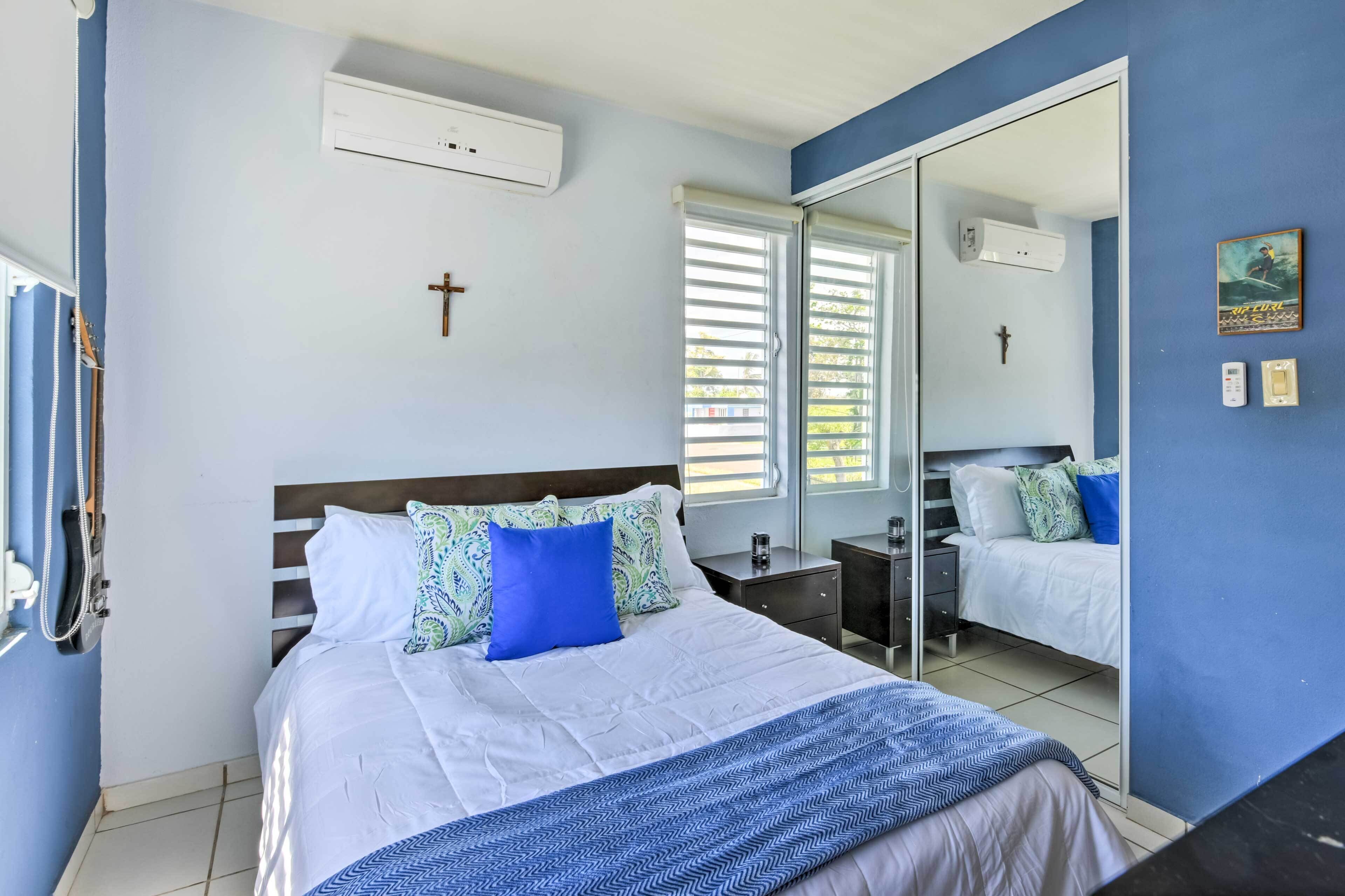 A bedroom with a bed, bedside tables, a mirror, and a cross on the wall.