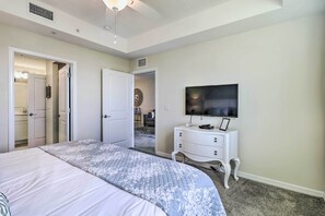 A bedroom with a bed, a dresser, a television, and an open door leading to a bathroom. - Kissimmee Condo ~ 10 Mi to Disney Attractions (Kissimmee)