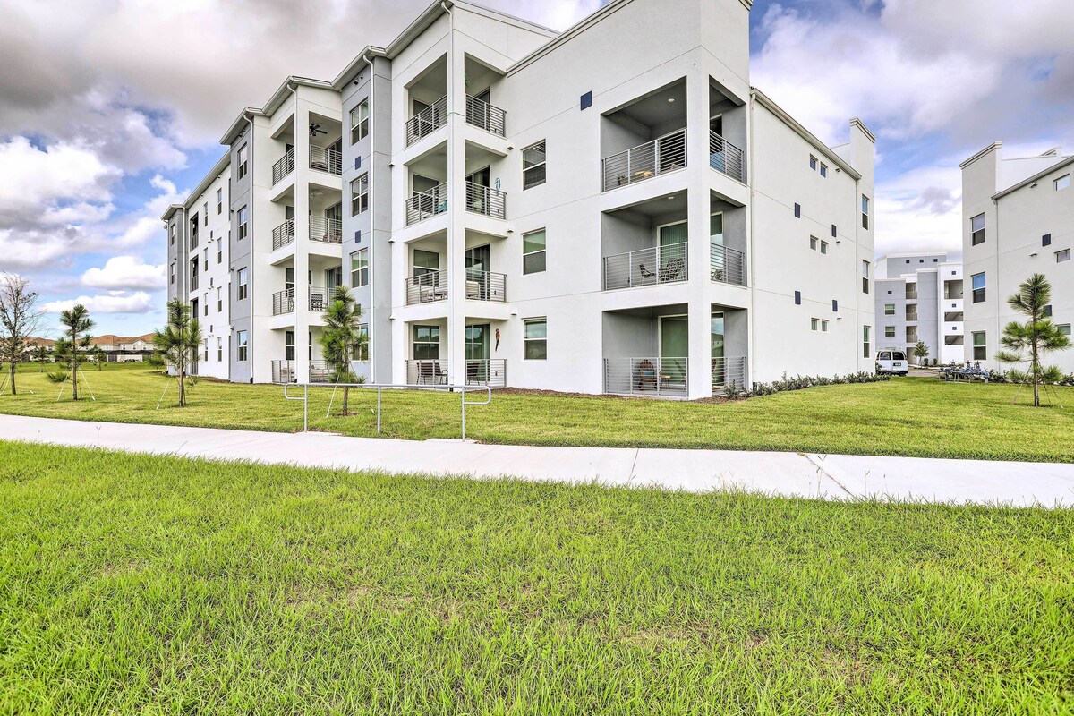 A multi-story residential building with balconies, a grassy lawn, and a clear sky.