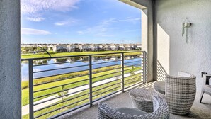 A balcony with wicker furniture, a view of a water body, and houses in the background. - Kissimmee Condo ~ 10 Mi to Disney Attractions (Kissimmee)