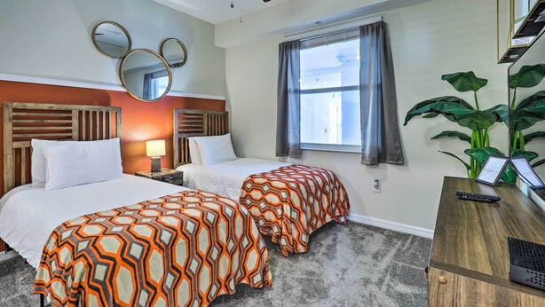 A hotel room with two beds, a ceiling fan, a large window with curtains, a desk with a laptop, and a potted plant. - Kissimmee Condo ~ 10 Mi to Disney Attractions (Kissimmee)