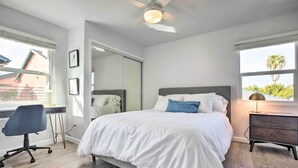 Um quarto com cama, escrivaninha e cadeira.