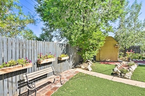 A wooden fence with flower planters, a bench, a small shed, and a well-maintained lawn.