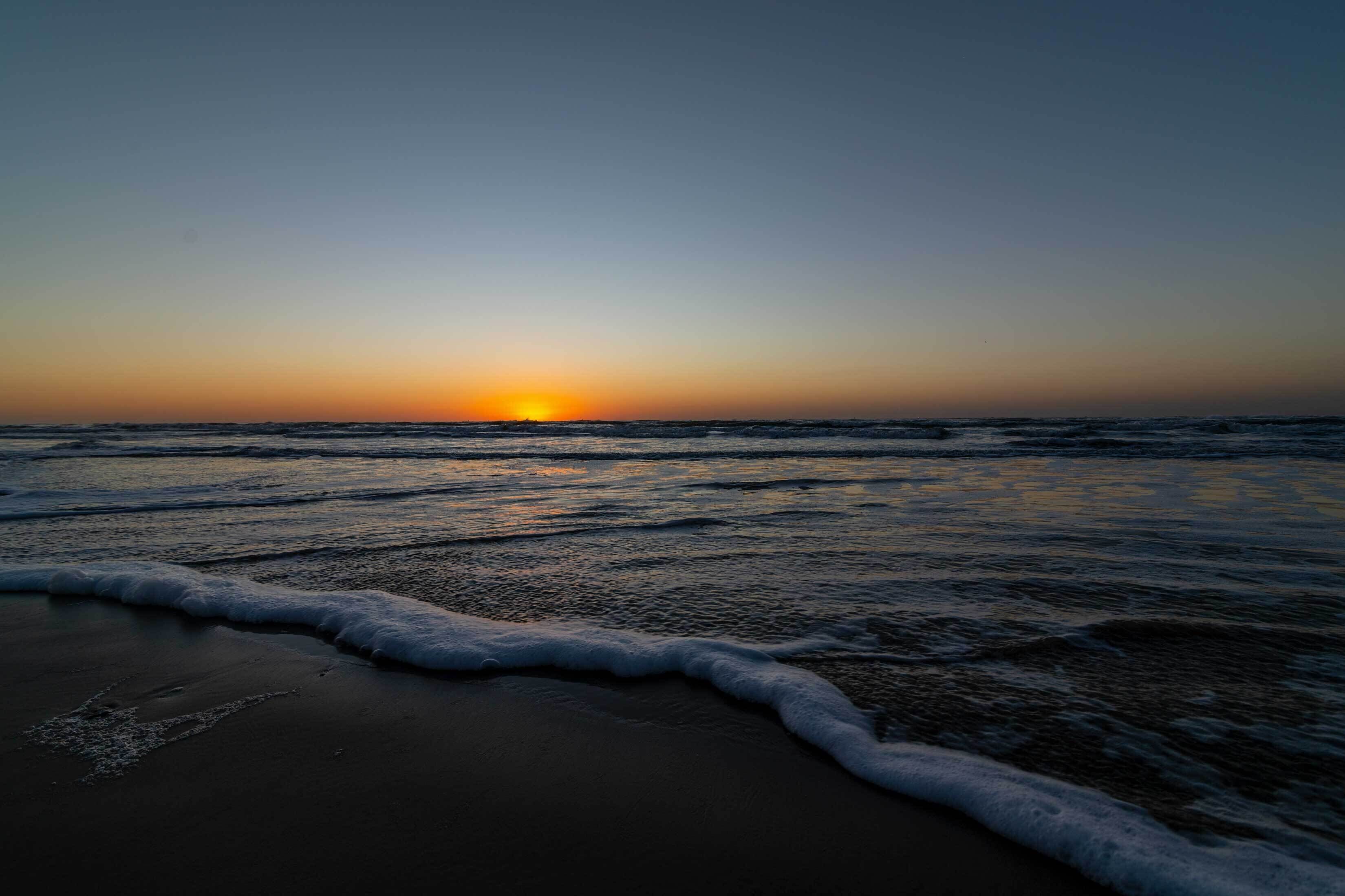 Una playa al atardecer con olas que acarician suavemente la orilla.