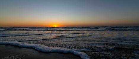 Una playa al atardecer con olas que acarician suavemente la orilla.