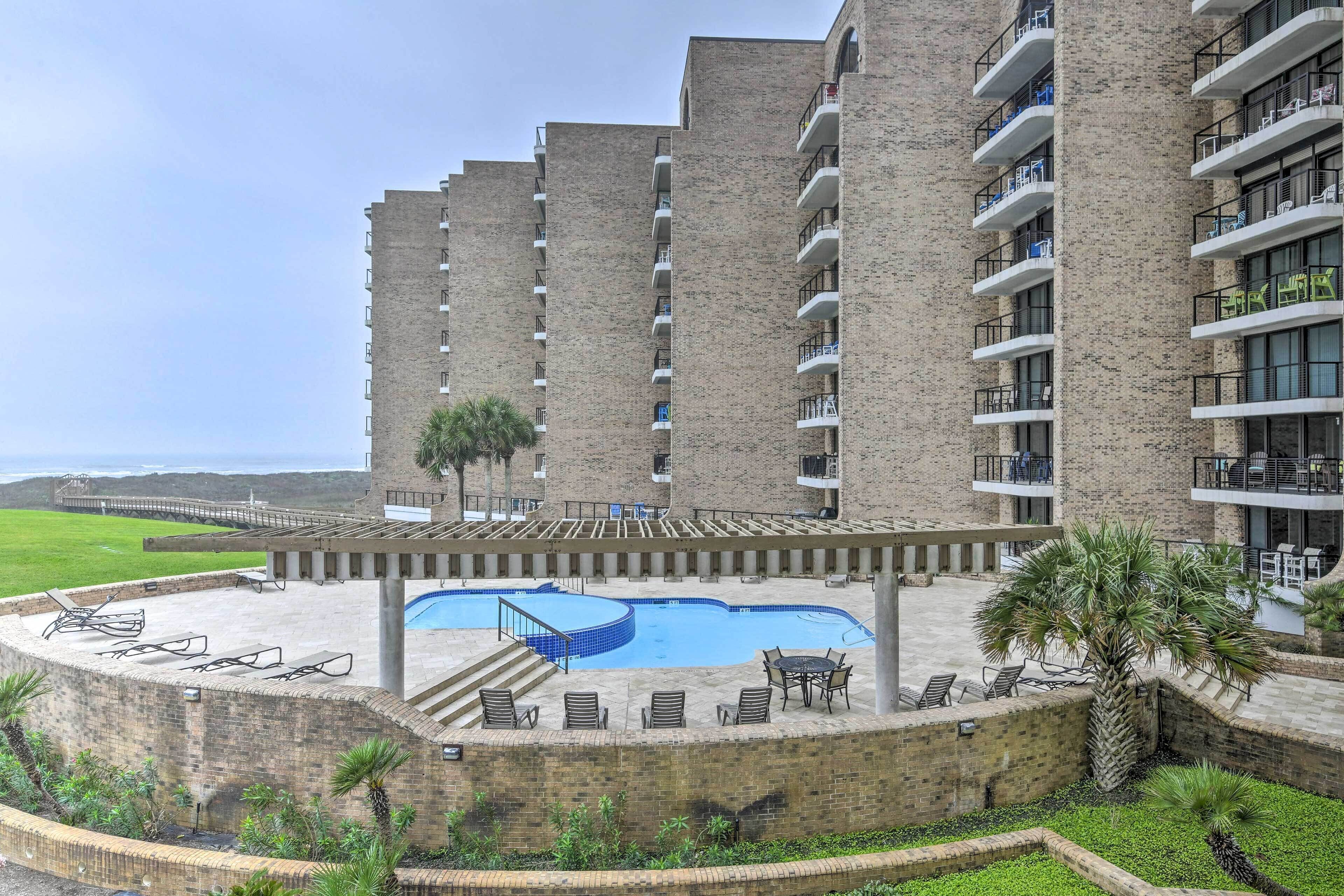 Un hotel de varios pisos con piscina, mobiliario exterior y vista al océano.