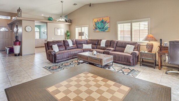 A spacious living room with a large sectional sofa, a coffee table, and a chessboard. - Heated Pool at 3 BR Home: 5 Mi to Coachella! (La Quinta)