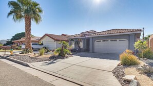 A residential house with a garage, a driveway, and a well-maintained garden with palm trees and shrubs. - Heated Pool at 3 BR Home: 5 Mi to Coachella! (La Quinta)