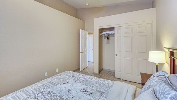 A hotel room with a bed, a ceiling fan, a door leading to a closet, and a lamp. - Heated Pool at 3 BR Home: 5 Mi to Coachella! (La Quinta)
