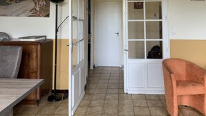 Une pièce comprenant une table à manger, un canapé, un lampadaire et une porte donnant sur une autre pièce.