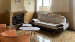 Un salon avec une cheminée, un canapé et deux petites tables.