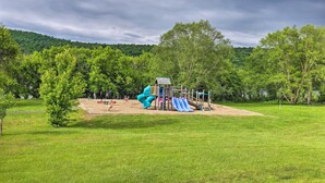A playground with slides and climbing structures in a grassy park area with trees and a hill in the background. - Private Retreat w/ Deck: 1 Mi From Cowanesque Lake (Lawrenceville)
