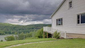 A white house with a wooden deck and a view of a lake and forested hills. - Private Retreat w/ Deck: 1 Mi From Cowanesque Lake (Lawrenceville)