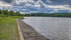 A riverside view with a concrete walkway, picnic tables, and a forested hill in the background. - Private Retreat w/ Deck: 1 Mi From Cowanesque Lake (Lawrenceville)