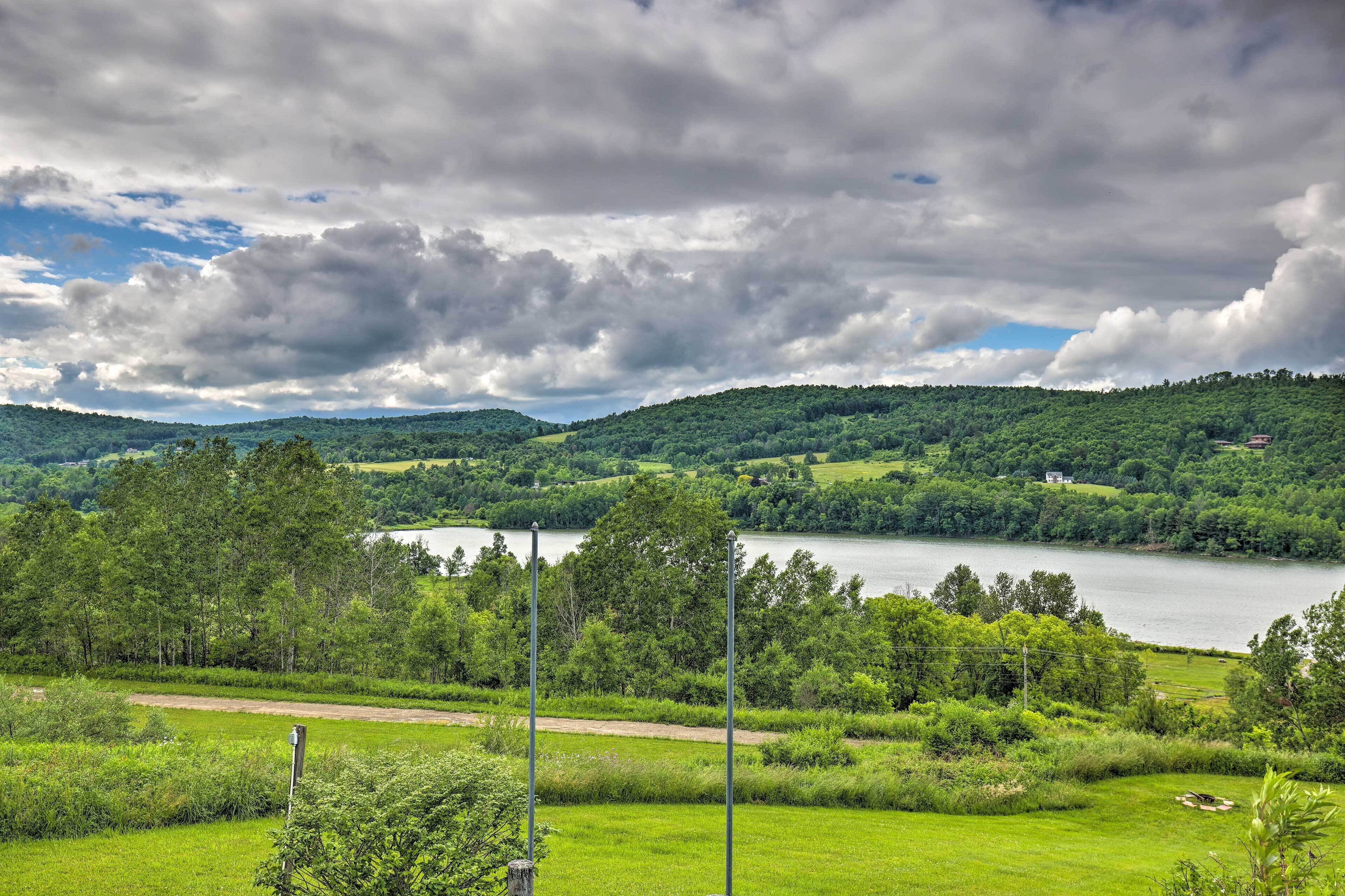 A lush green landscape with a lake, trees, and a distant house.