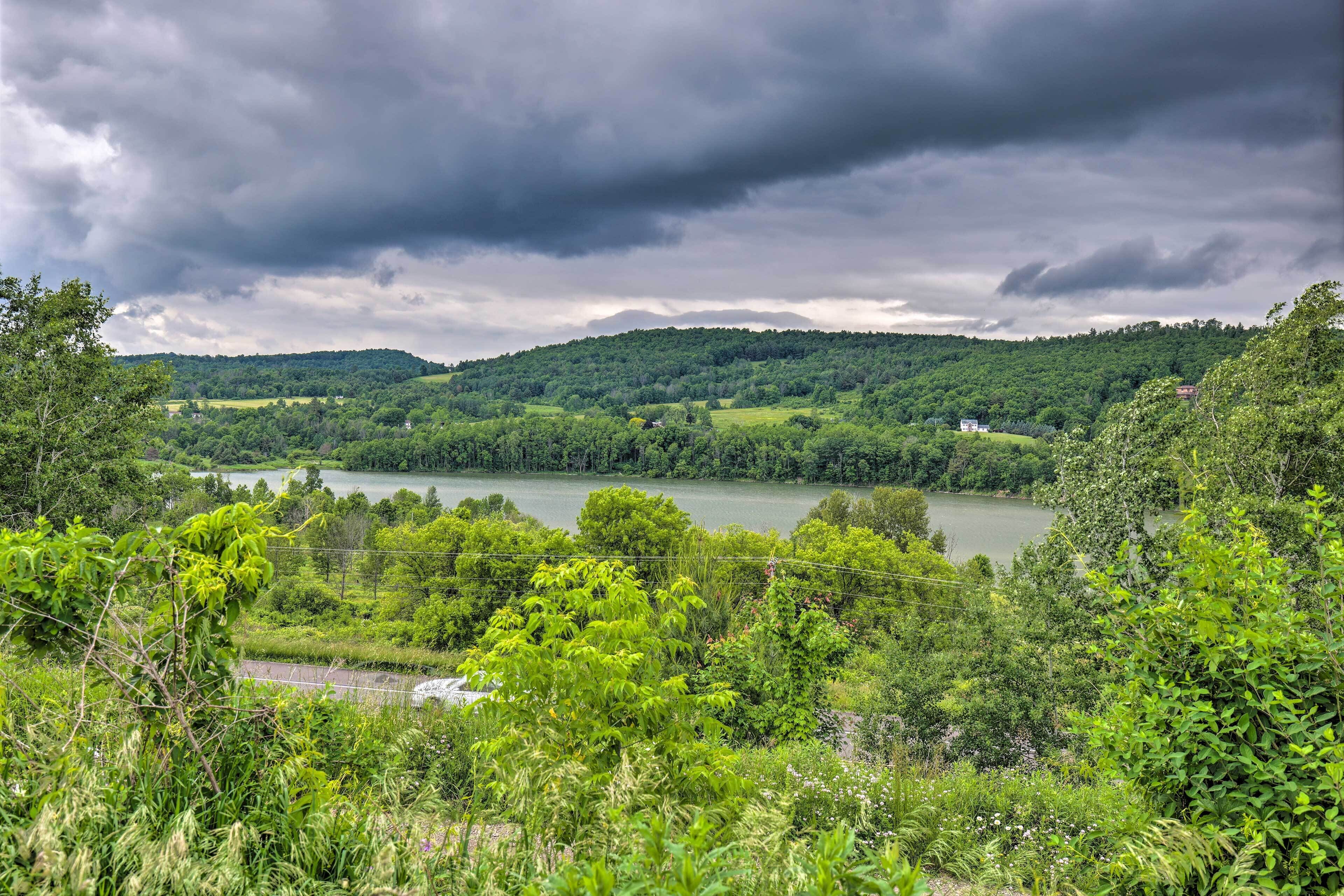 A lush green landscape with a lake, hills, and a cloudy sky.