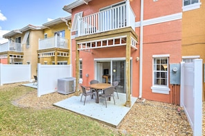 A residential building with a patio area featuring a table and chairs, a sliding glass door, and a small deck with a railing. - Cozy Kissimmee Townhome ~ 8 Mi to Disney World! (Kissimmee)