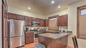 A modern kitchen with stainless steel appliances, wooden cabinets, and a granite countertop. - Cozy Central Glenwood Springs Condo w/ 2 Decks! (Glenwood Springs)