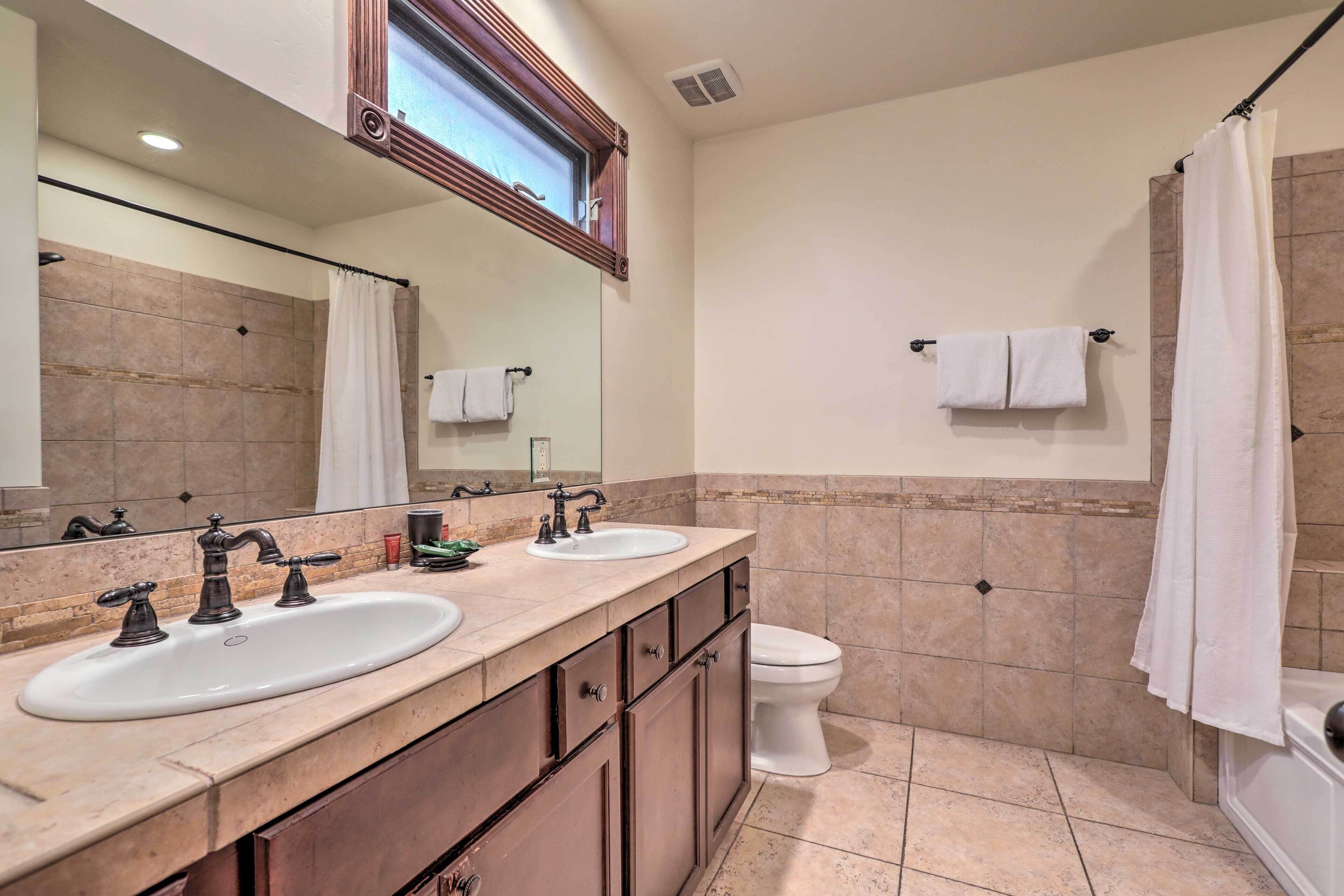 A bathroom with two sinks, a toilet, and a shower.