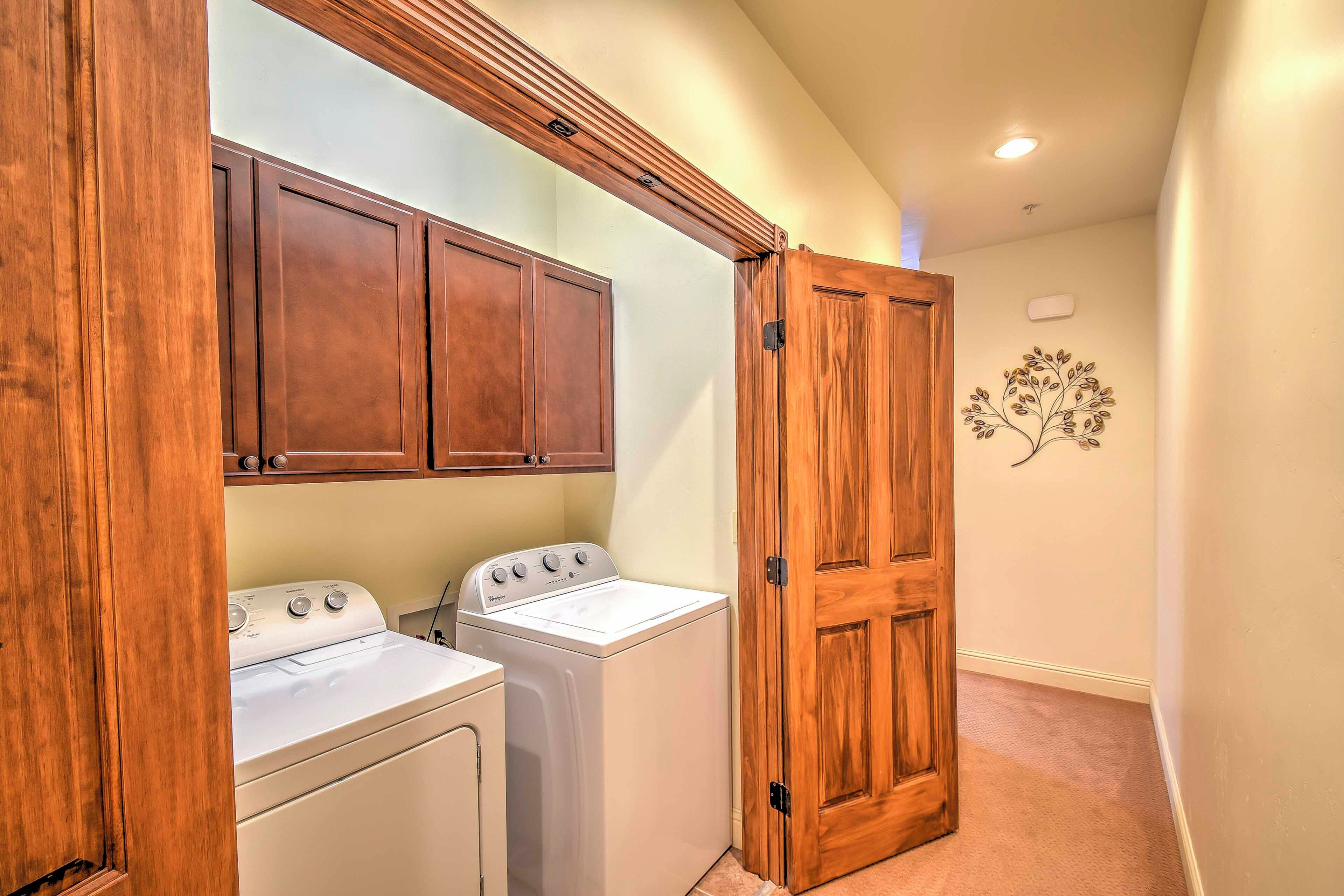 A laundry room with wooden cabinets, a washing machine, and a dryer.