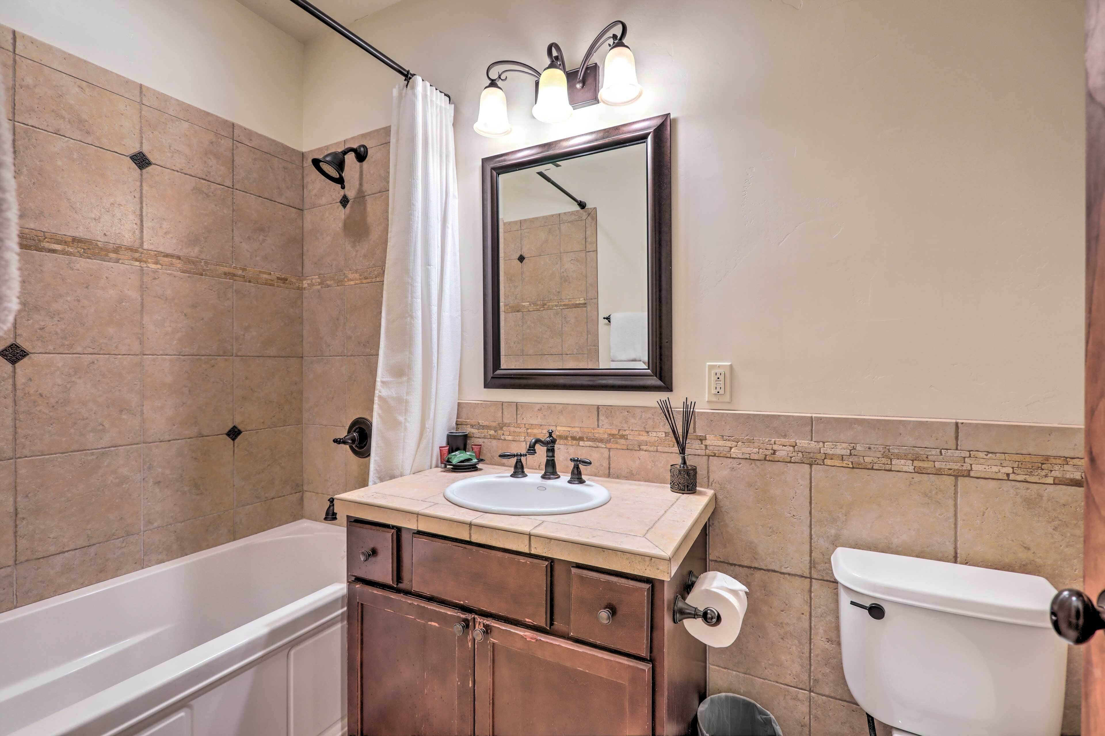 A bathroom with a bathtub, sink, mirror, and toilet.