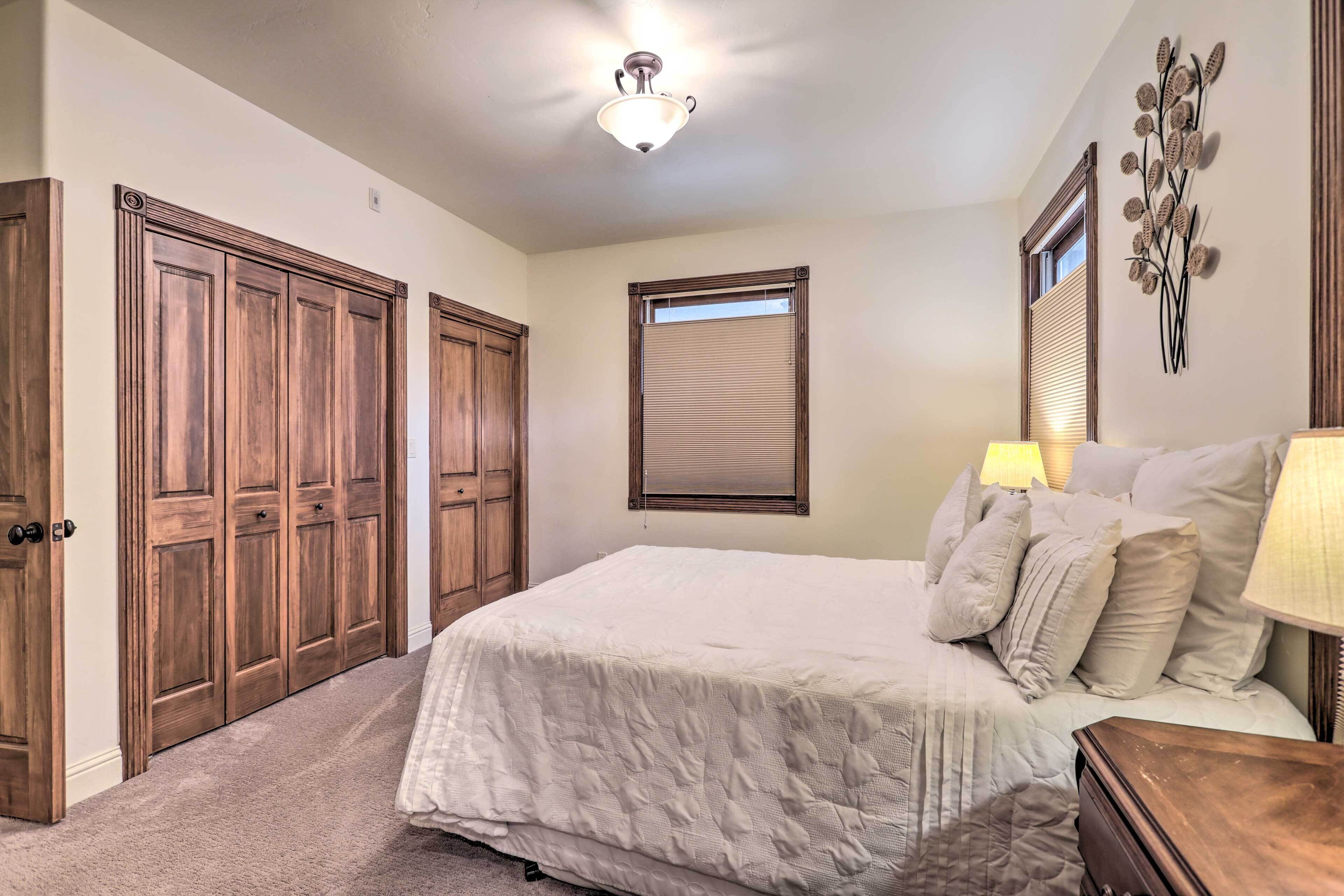 A bedroom with a large bed, wooden wardrobe, and a ceiling light fixture.