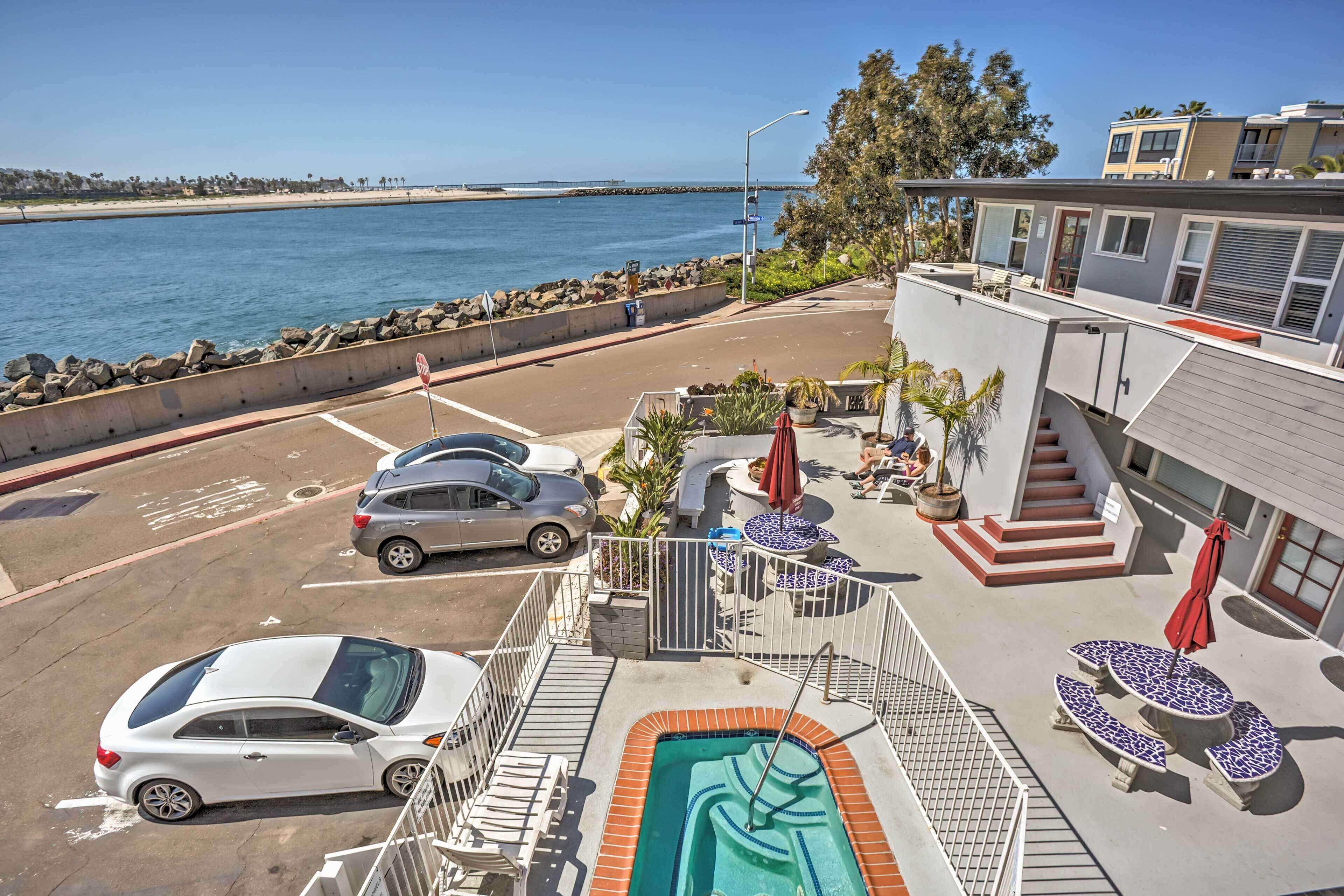 Uma área de piscina com hidromassagem, mobiliário de exterior e vista para o oceano.