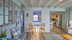 A modern kitchen with stainless steel appliances, a dining area with two wooden chairs, and a view of the outside through a window. - Chic Bay View Condo < 10 Miles to Dtwn San Diego! (San Diego)