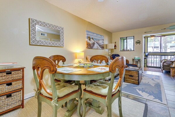 A dining area with a round table, four chairs, a sideboard, and a mirror on the wall.