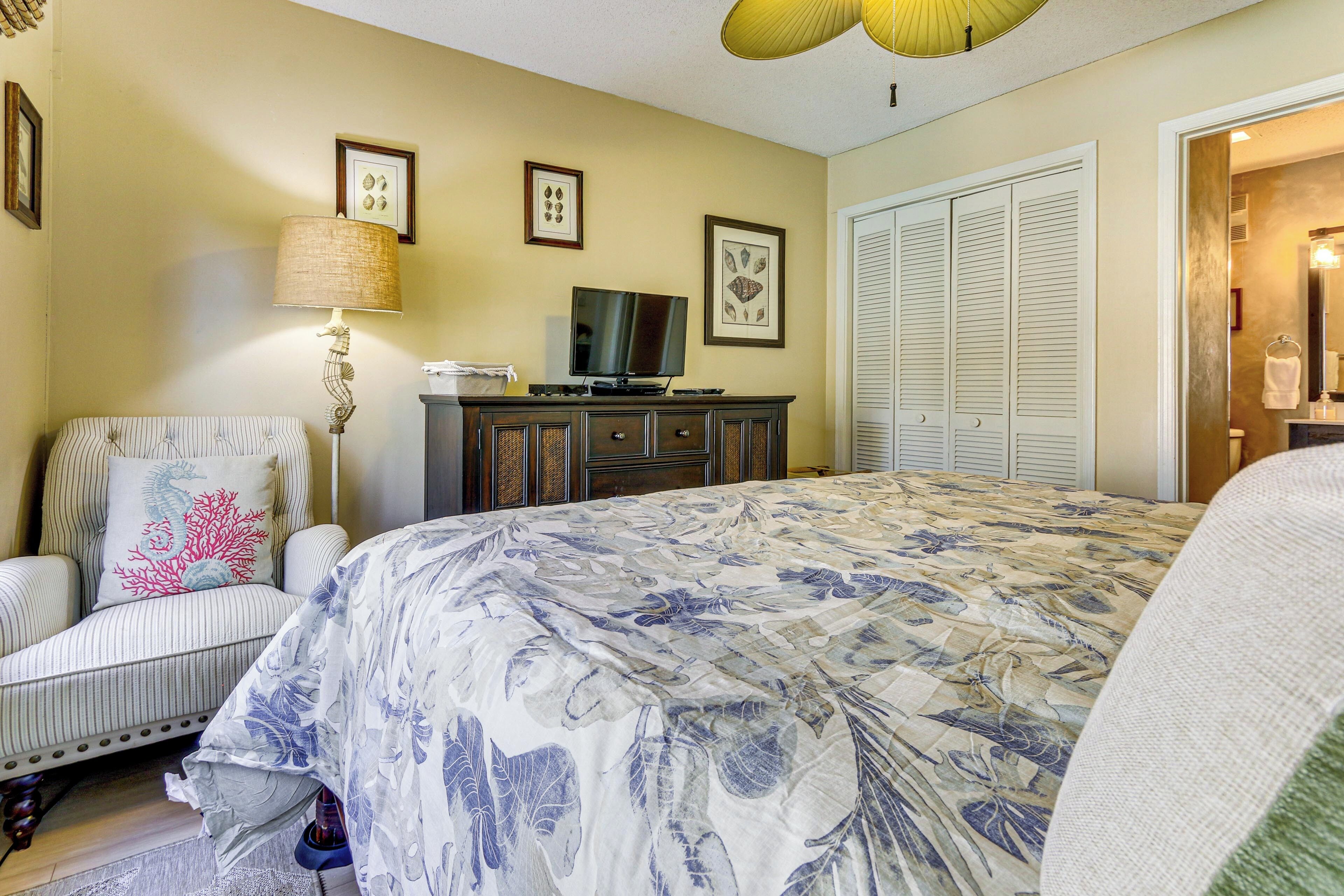 Une chambre à coucher avec un lit, une chaise, un téléviseur et une commode.