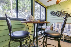 A room with a green wall, a large window, two black chairs, a small table, and a wall decoration of fish.
