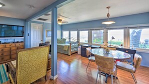 A spacious living room with a television, a dining area with a round table and chairs, a sofa, and a large window offering a view of the outdoors. - Riverfront St Augustine Retreat, Near Boat Launch! (St. Augustine)