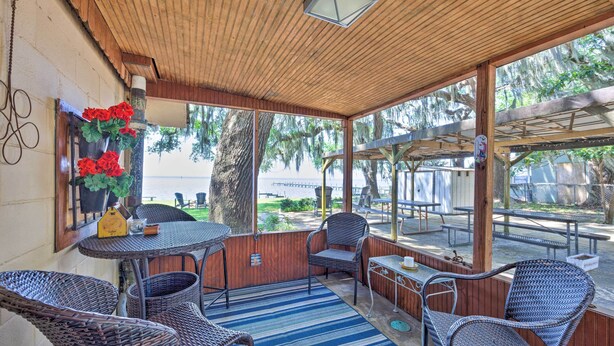 A covered outdoor seating area with wicker furniture, a blue striped rug, and a view of the water. - Riverfront St Augustine Retreat, Near Boat Launch! (St. Augustine)