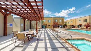 Un espacio al aire libre techado con piscina, sillas de descanso y mesas.
