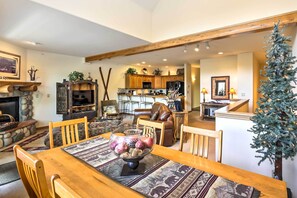 A spacious living room with a wooden dining table, a fireplace, and a kitchen in the background. - 7 Mi to Skiing: Main St Frisco Condo w/ Balcony! (Frisco)