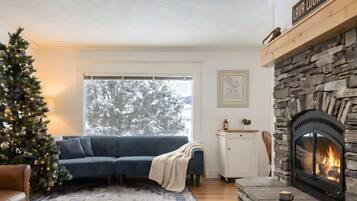 Una sala acogedora con chimenea, árbol de Navidad y sofá azul.