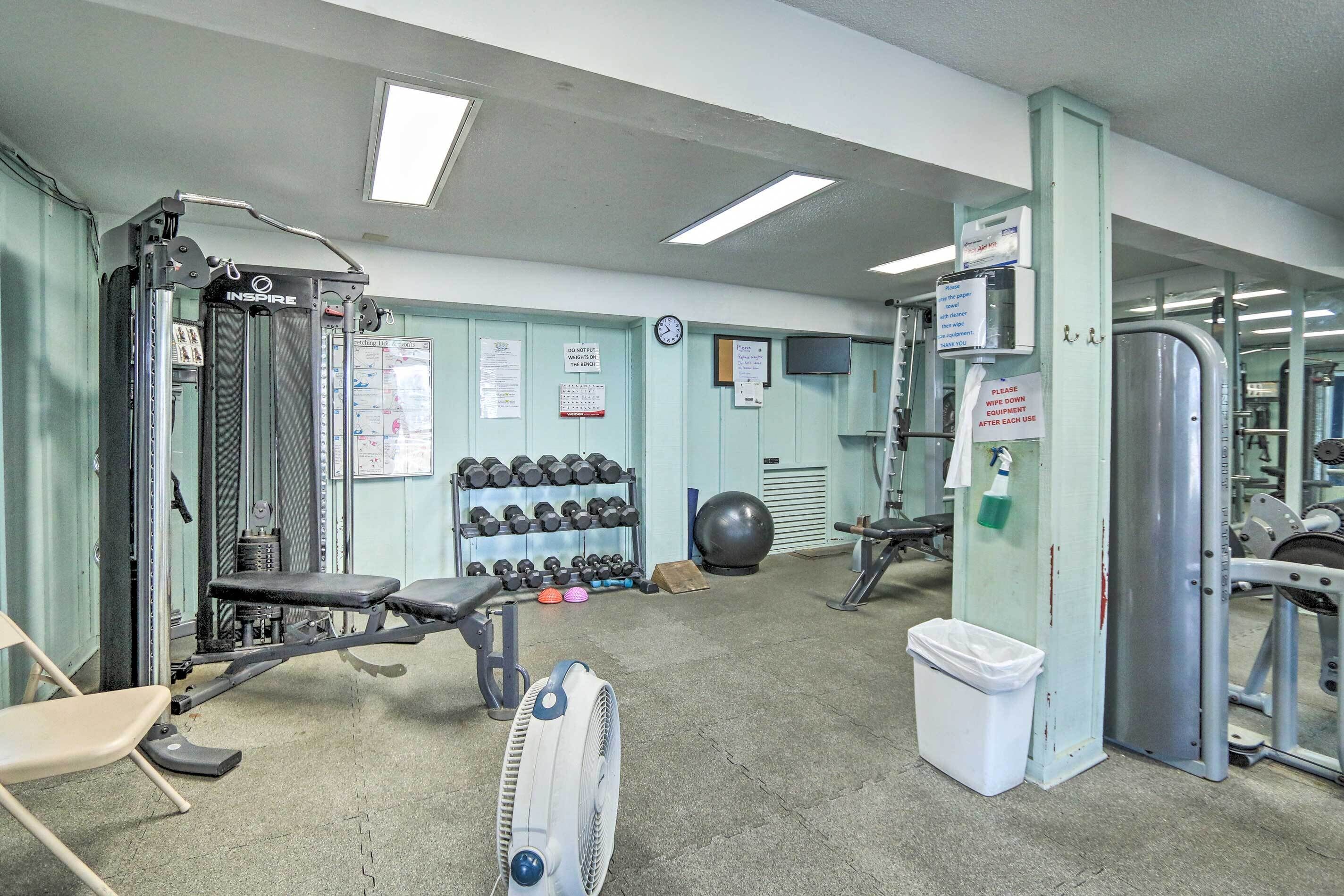 A gym with exercise equipment, a fan, and a trash bin.