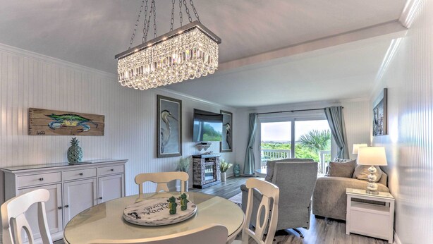 Een eethoek met een kroonluchter, witte stoelen, een ronde tafel met dienblad en uitzicht op de omgeving.
