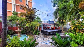 A patio area with a pool, outdoor seating, and lush greenery. - Luxurious San Juan Villa w/ Pool - Walk to Beach! (San Juan)