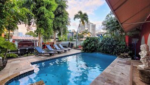 A swimming pool with lounge chairs, surrounded by greenery and a stone deck. - Luxurious San Juan Villa w/ Pool - Walk to Beach! (San Juan)