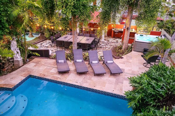 Un área de piscina con sillones de descanso, una mesa de comedor y un jacuzzi.