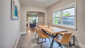 A modern dining area with a wooden table and four chairs, a large window with blinds, and a ceiling light.