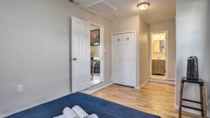 Een slaapkamer met een bed, een houten kruk en een badkamer door een open deur.