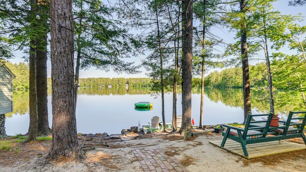 A lakeside deck with a brick pathway, a green deck chair, and a floating dock.