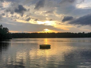 Un lac paisible, avec un bateau au premier plan et une rive boisée en arrière-plan.