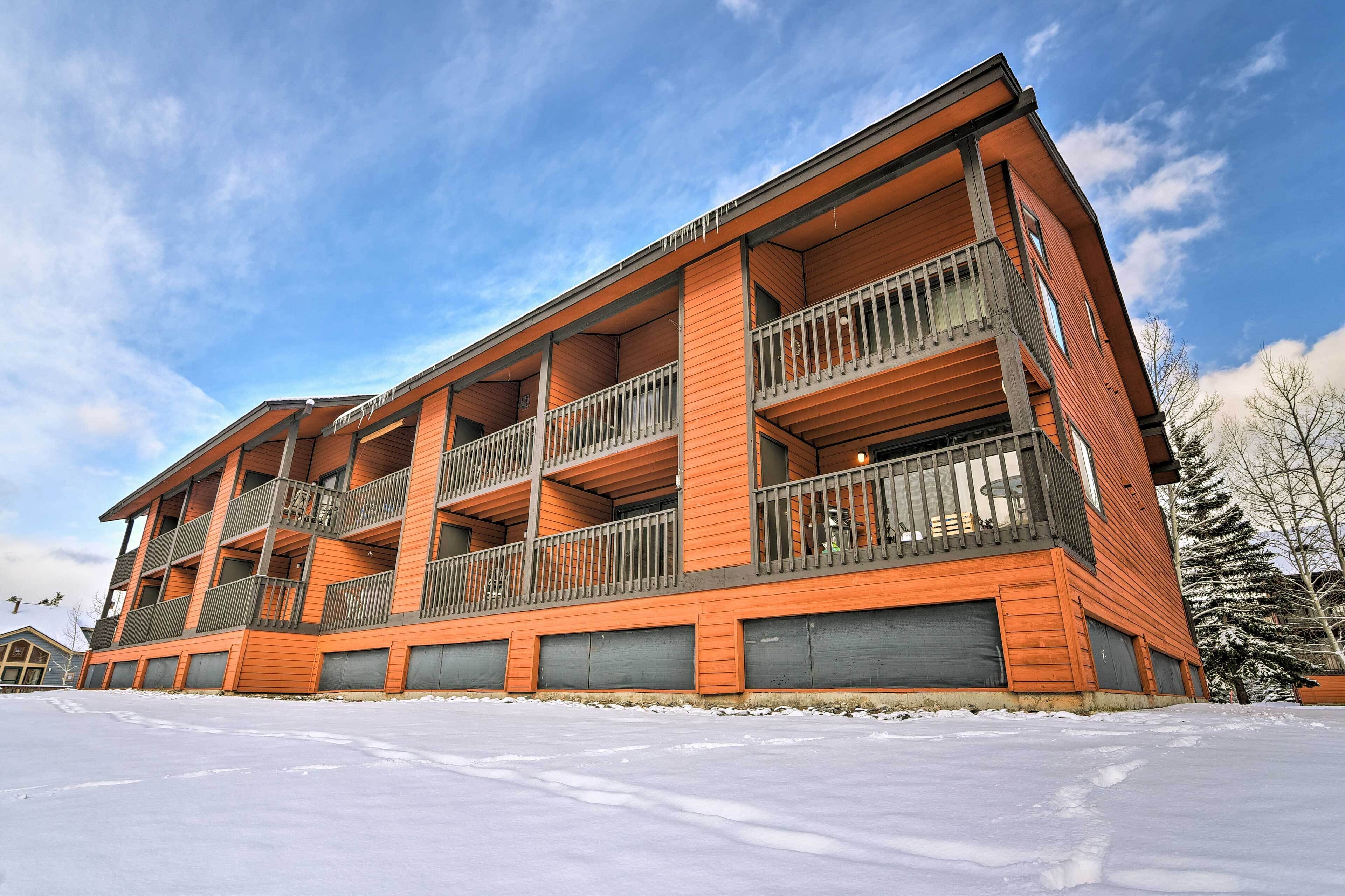 A multi-story building with balconies and large windows, surrounded by snow.