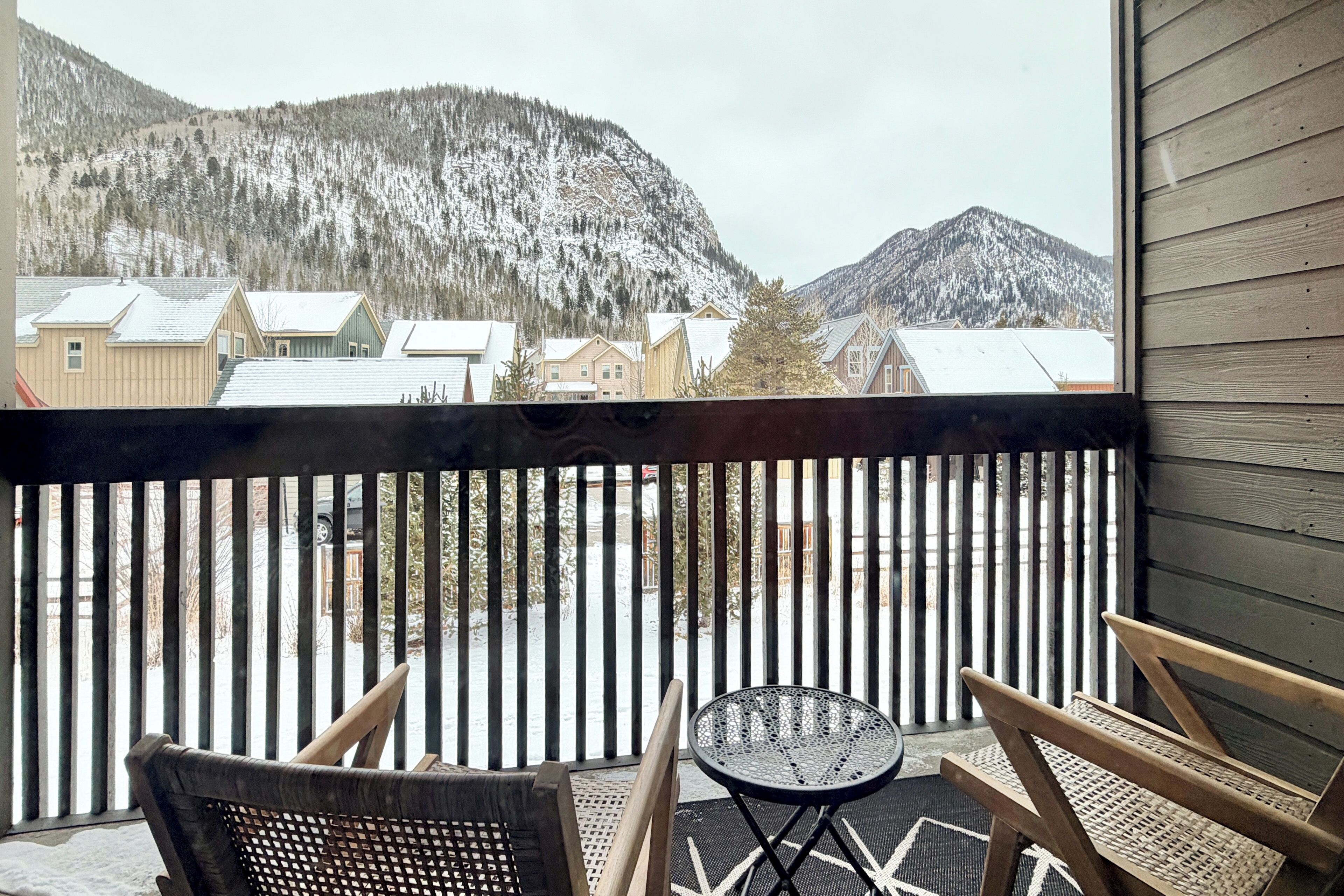 A balcony with a view of snow-covered mountains and houses.