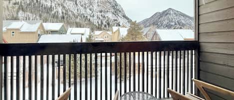 A balcony with a view of snow-covered mountains and houses.